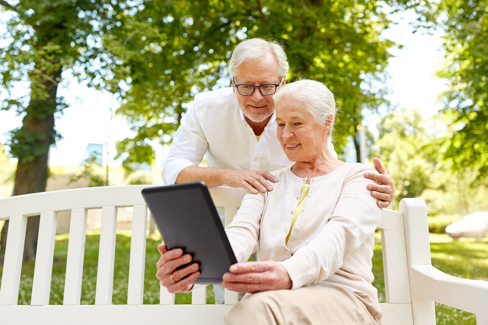 Senior couple outside using m.Care tablet to speak with care team